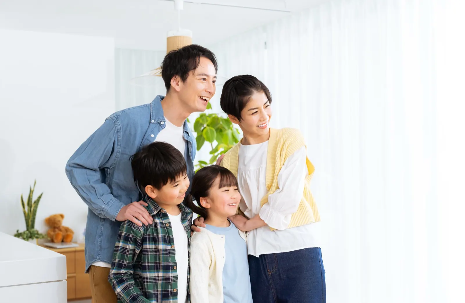 明るいリビングで寄り添う日本人の家族4人