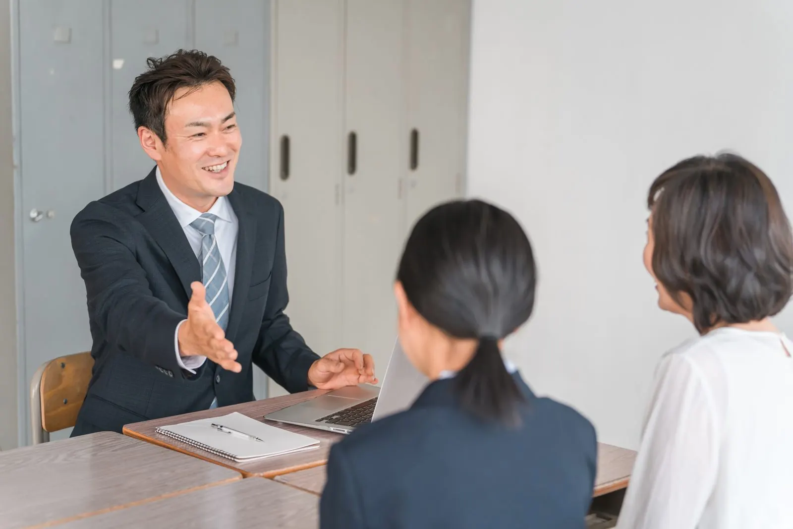 学校の一室で先生から説明を受ける母親と娘