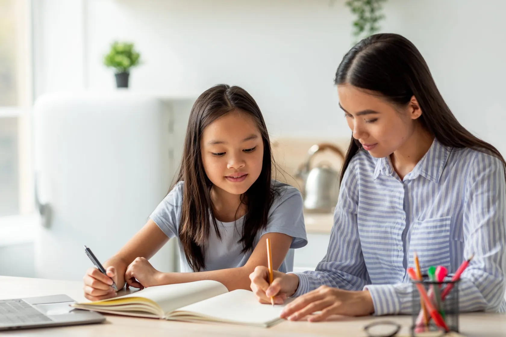 ノートに書き込む娘と、となりで教える母親